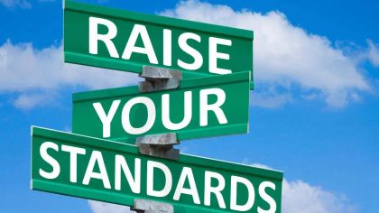 Three green street signs overlapping with the words "Raise Your Standards" against a blue sky with clouds.