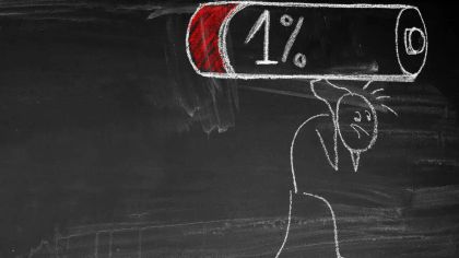 A chalk drawing of a figure looking worried under a battery icon indicating 1% charge on a blackboard.