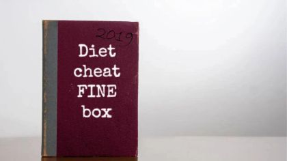 A maroon book titled "Diet cheat FINE box" from 2019, displayed on a wooden surface.