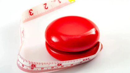 A red round object placed beside a measuring tape on a white background.