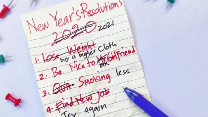 A notepad with handwritten New Year's resolutions for 2020, featuring items crossed out and a blue pen beside it.