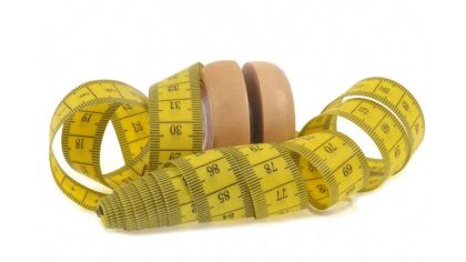 A yellow measuring tape coiled around two brown circular objects, resembling weights or blocks.