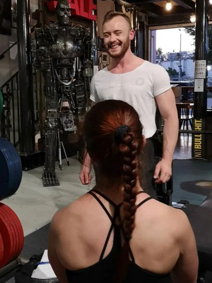 Picture of coach Manuel smiling while talking to a client in the gym