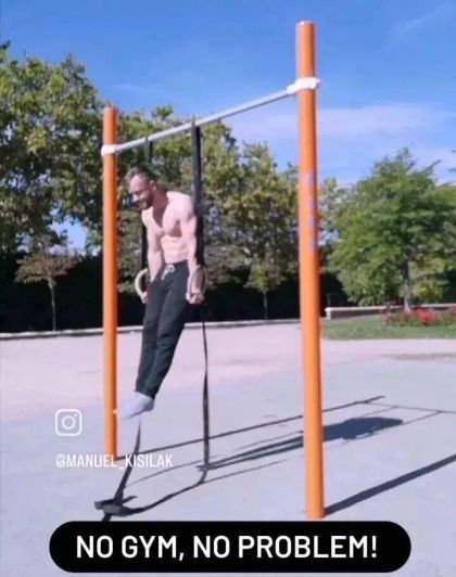 A shirtless man performs a muscle-up on outdoor gym rings, with trees in the background and text overlay "No gym, no problem!"