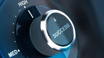 A close-up of a dial labeled "SUCCESS," set between low and high settings, indicating a focus on achievement.