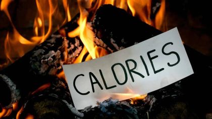 A piece of paper with the word "CALORIES" is placed on burning logs and flames.