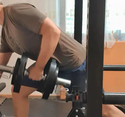A person performs a bent-over row exercise with a dumbbell in a home gym setting.