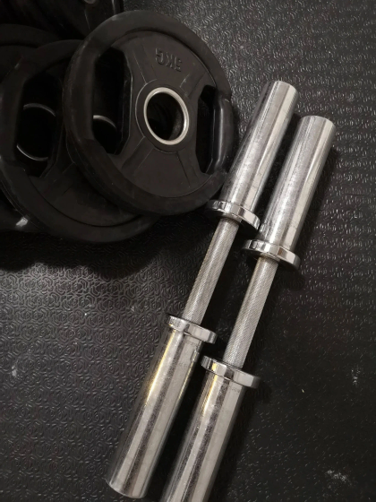 Two chrome barbells with weight plates on a textured black surface.